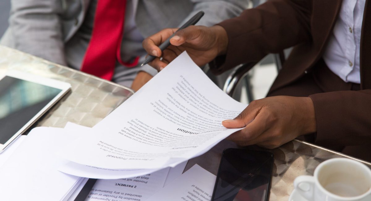 Businessman consulting legal expert in coffee shop. Closeup of business man and woman sitting in cafe and reading documents. Paperwork concept